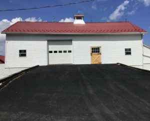 Garage with red metal roof and farm door.